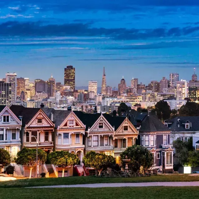 Le famose Painted女士 di Alamo Square sono ritratte di fronte allo skyline di San Francisco al tramonto.